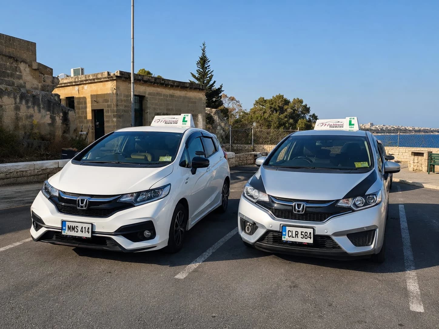 Two Mariani Honda learner cars with branded roof signs